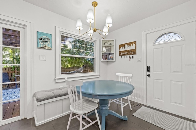 dining space featuring an inviting chandelier, plenty of natural light, and dark tile patterned flooring