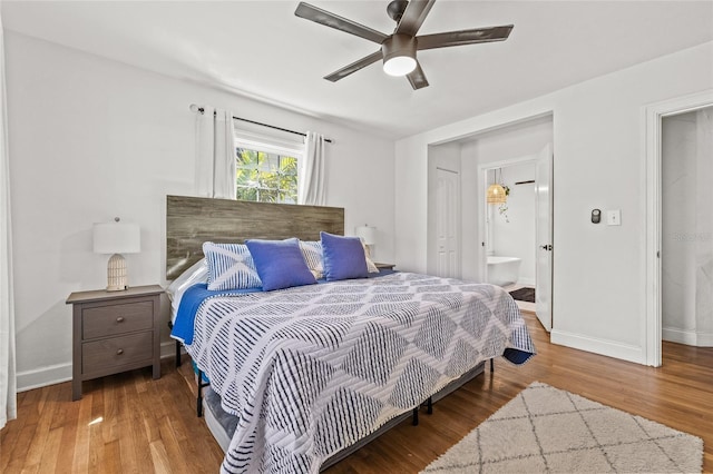 bedroom with ceiling fan, baseboards, wood finished floors, and ensuite bathroom