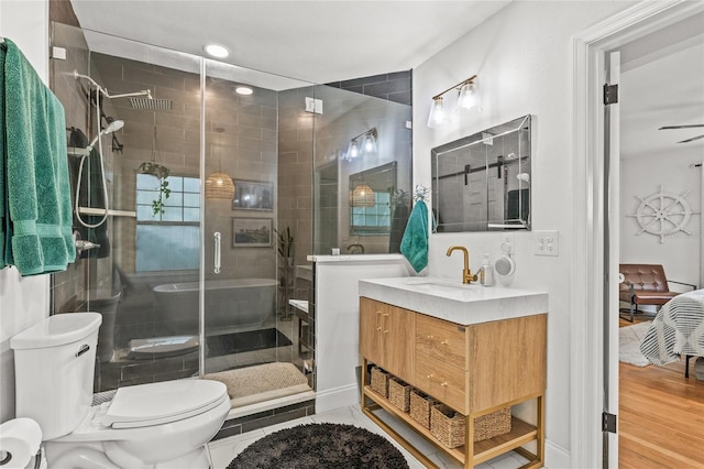 bathroom with toilet, a shower stall, wood finished floors, and vanity