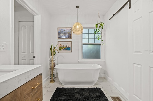 bathroom featuring visible vents, baseboards, marble finish floor, a freestanding bath, and vanity