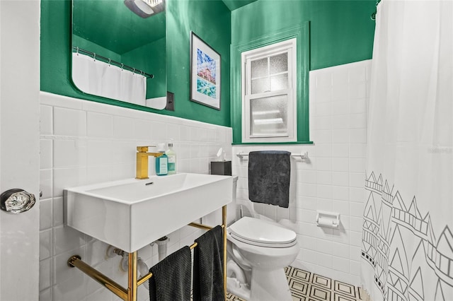 full bath with a wainscoted wall, tile patterned flooring, toilet, and tile walls