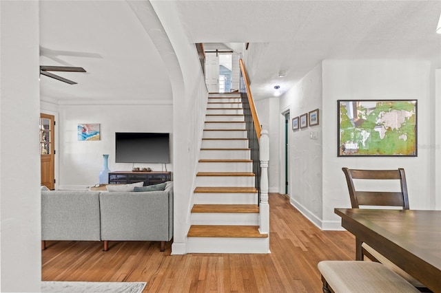 staircase featuring ceiling fan, baseboards, and wood finished floors