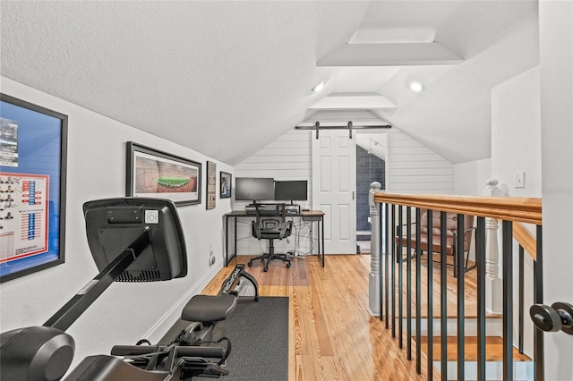 workout room featuring vaulted ceiling, a textured ceiling, and wood finished floors