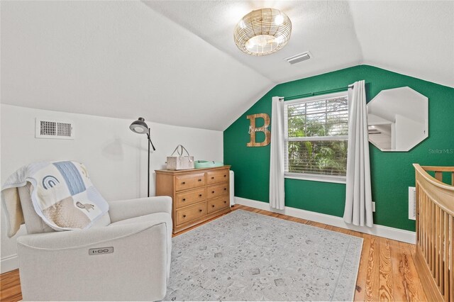 living area featuring lofted ceiling, wood finished floors, visible vents, and baseboards