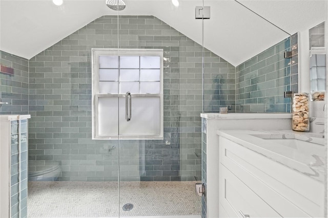 full bathroom with vaulted ceiling, vanity, a shower stall, and tile walls