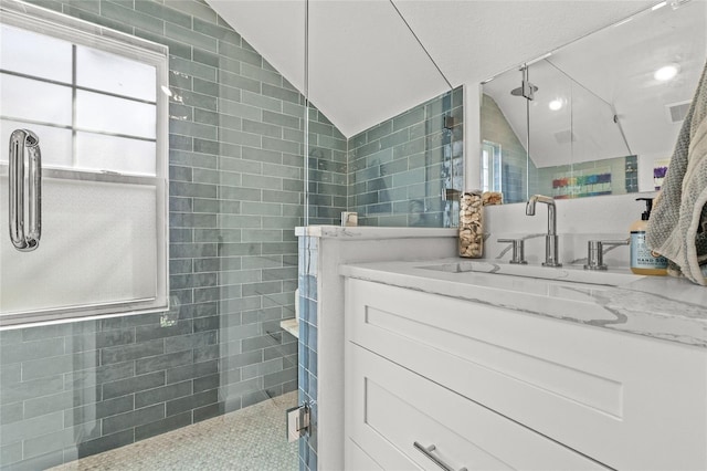 bathroom with a shower stall, vaulted ceiling, tile walls, and vanity