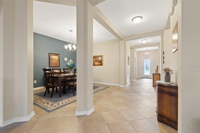 entryway featuring an inviting chandelier, light tile patterned floors, and baseboards