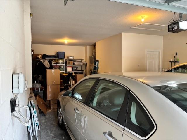 garage with concrete block wall, water heater, and a garage door opener