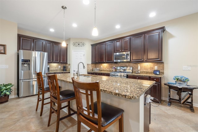 kitchen featuring stainless steel appliances, dark brown cabinets, light stone counters, and a kitchen breakfast bar