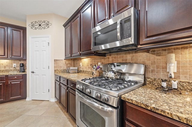 kitchen with tasteful backsplash, light stone counters, stainless steel appliances, dark brown cabinets, and light tile patterned flooring