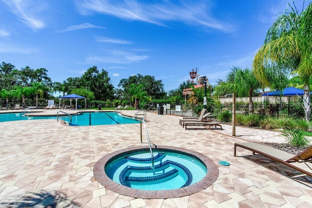 pool featuring fence, a community hot tub, and a patio area