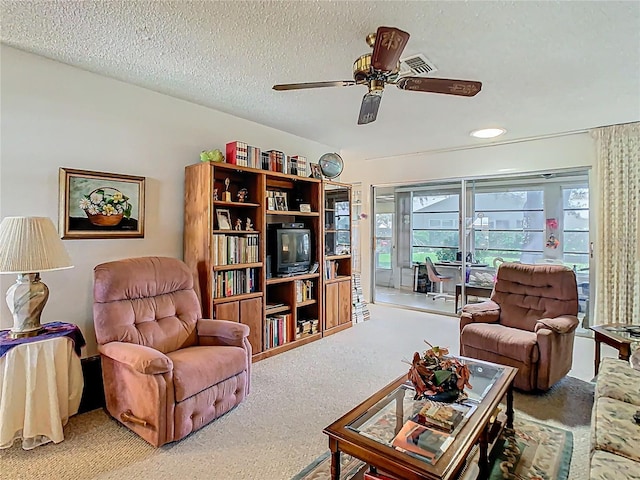 living room featuring carpet, visible vents, ceiling fan, and a textured ceiling