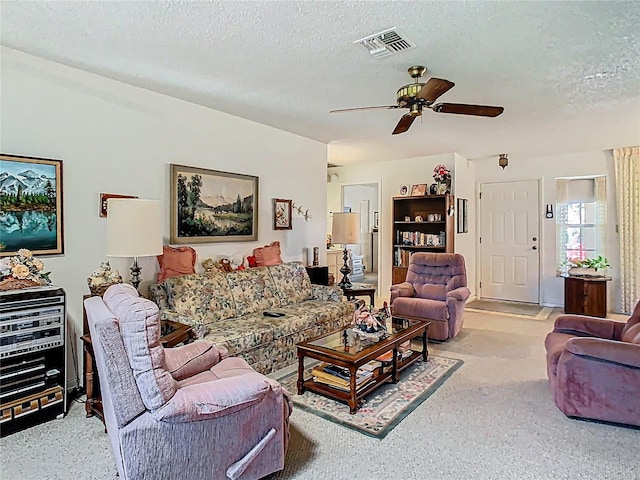 living room with a textured ceiling, carpet flooring, visible vents, and a ceiling fan