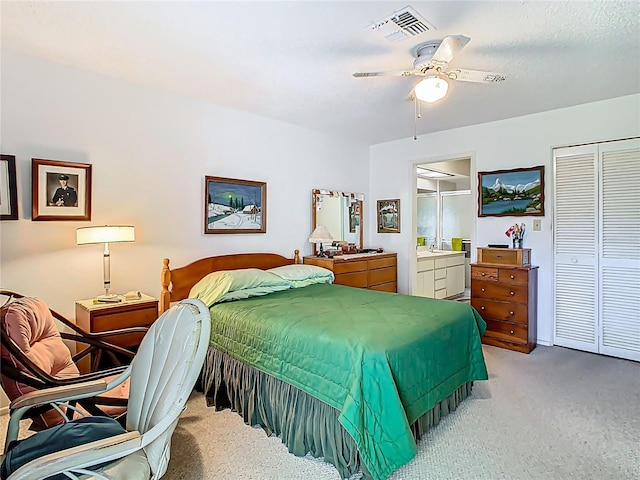 bedroom with light carpet, visible vents, a ceiling fan, ensuite bathroom, and a closet