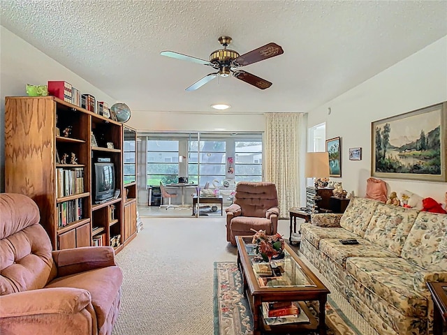 living area featuring carpet, ceiling fan, and a textured ceiling