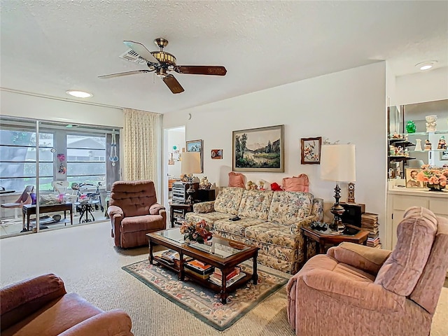 living room with a ceiling fan, carpet flooring, and a textured ceiling