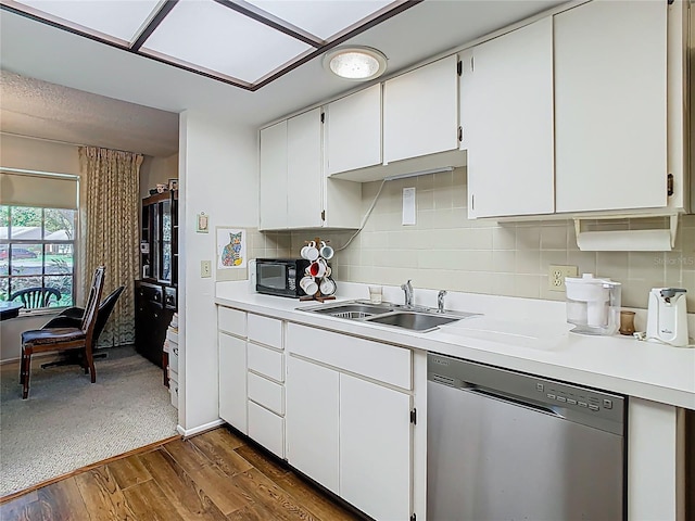 kitchen with light countertops, backsplash, stainless steel dishwasher, a sink, and black microwave