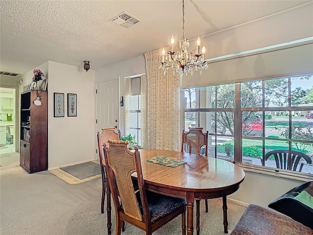 dining area with an inviting chandelier, baseboards, visible vents, and a textured ceiling