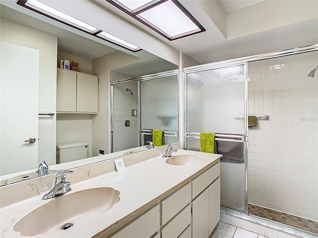 full bathroom featuring double vanity, a shower stall, toilet, and a sink