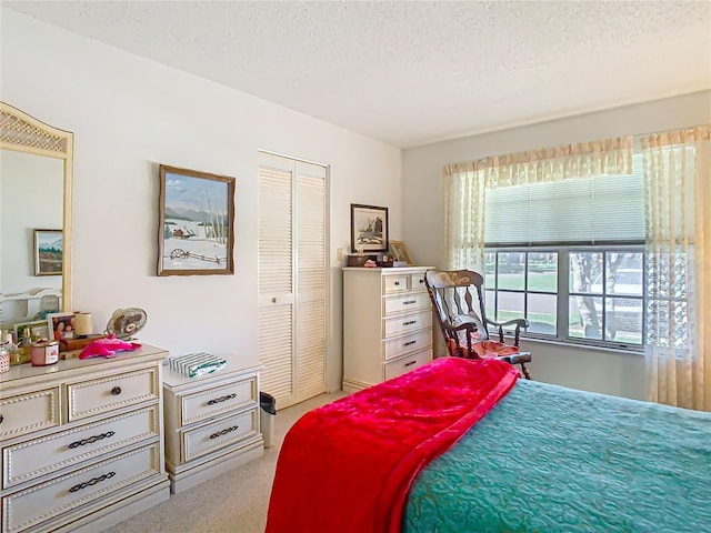 bedroom with a closet, light carpet, and a textured ceiling