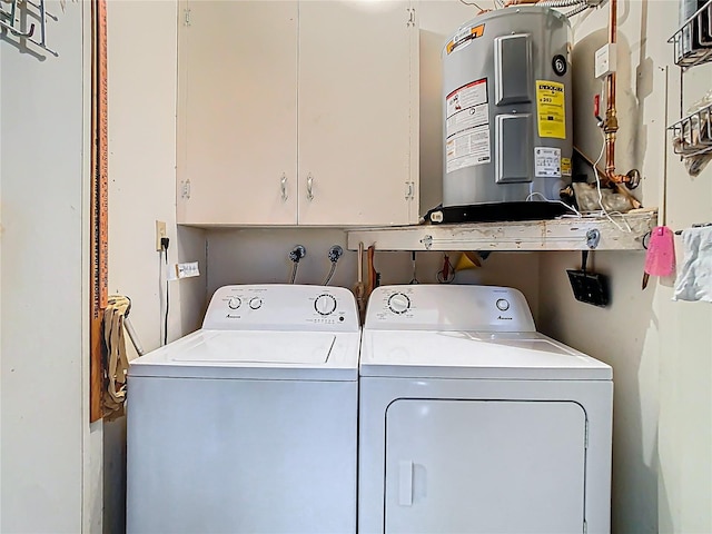 clothes washing area with water heater, cabinet space, and washer and clothes dryer