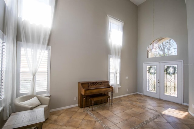 entrance foyer with french doors, a high ceiling, baseboards, and an inviting chandelier