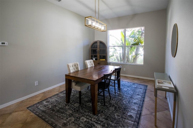 tiled dining room with baseboards and a notable chandelier