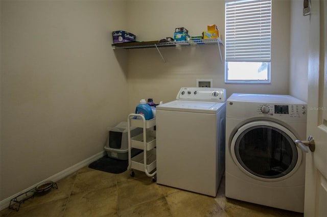 washroom featuring laundry area, baseboards, and separate washer and dryer