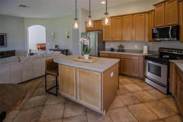 kitchen featuring arched walkways, stainless steel appliances, a kitchen island, a kitchen breakfast bar, and open floor plan