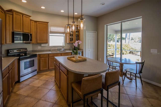 kitchen featuring a breakfast bar, recessed lighting, appliances with stainless steel finishes, a sink, and a kitchen island