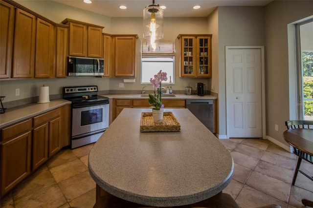 kitchen with appliances with stainless steel finishes, recessed lighting, pendant lighting, and brown cabinets