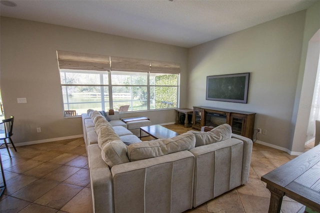 living area with baseboards and a glass covered fireplace