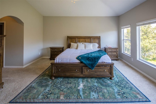 bedroom with baseboards, arched walkways, and light colored carpet