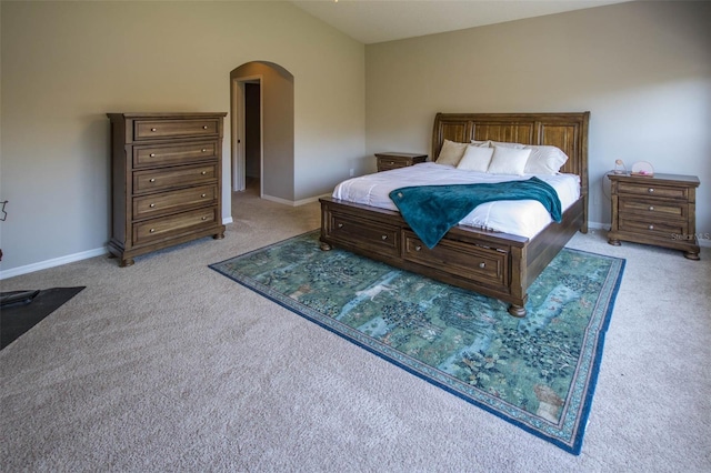 bedroom with lofted ceiling, baseboards, arched walkways, and light colored carpet