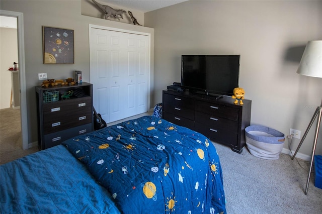 carpeted bedroom featuring a closet and baseboards