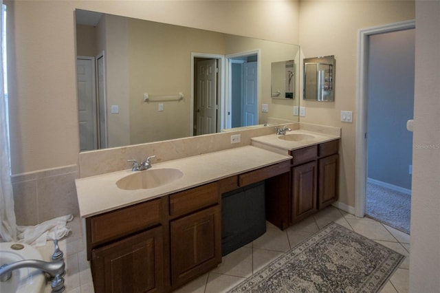 bathroom featuring double vanity, a sink, baseboards, and tile patterned floors