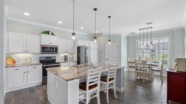 135 Cabana Way, Rotonda West, FL 33947 - kitchen with stainless steel appliances, a sink, dark wood-style floors, an island with sink, and tasteful backsplash