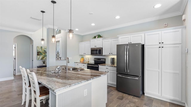 135 Cabana Way, Rotonda West, FL 33947 - kitchen featuring appliances with stainless steel finishes, a sink, arched walkways, light wood-type flooring, and white cabinetry