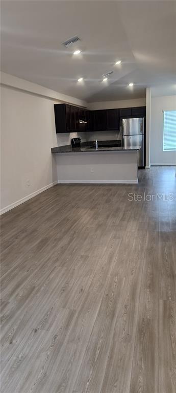 kitchen with visible vents, dark wood finished floors, freestanding refrigerator, dark countertops, and open floor plan