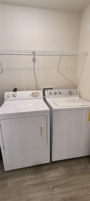 washroom featuring wood finished floors, washing machine and dryer, and laundry area