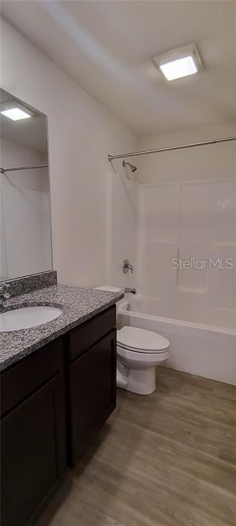 full bath featuring vanity, toilet, wood finished floors, and  shower combination