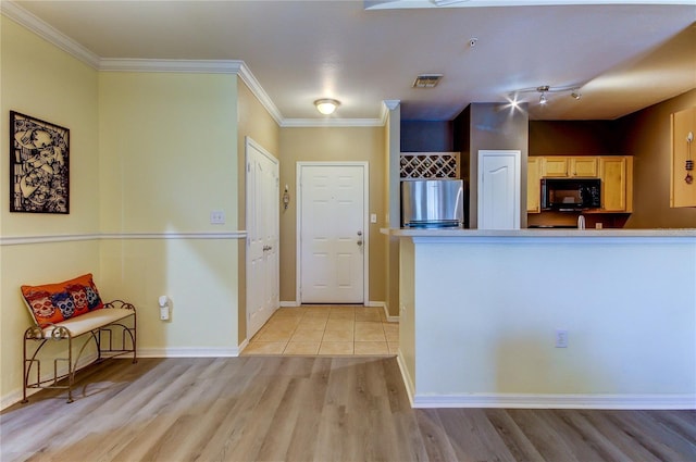 kitchen with visible vents, light wood-style flooring, ornamental molding, freestanding refrigerator, and black microwave