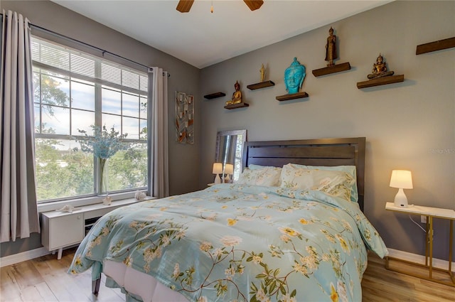 bedroom featuring a ceiling fan, light wood-style flooring, and baseboards