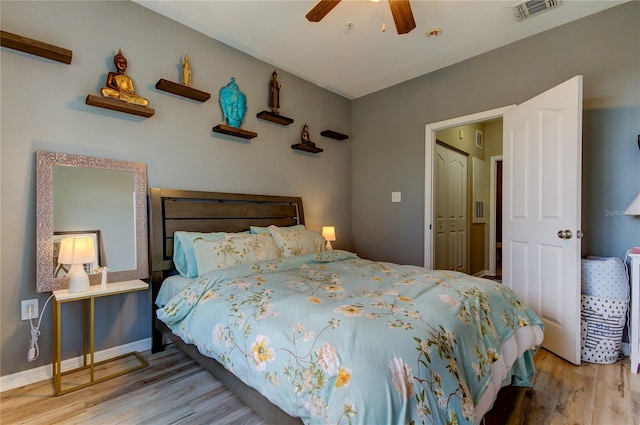 bedroom with baseboards, visible vents, ceiling fan, and wood finished floors