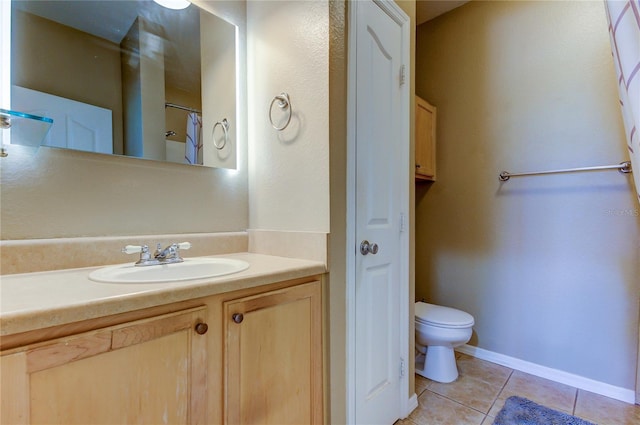 bathroom featuring toilet, vanity, baseboards, a closet, and tile patterned floors