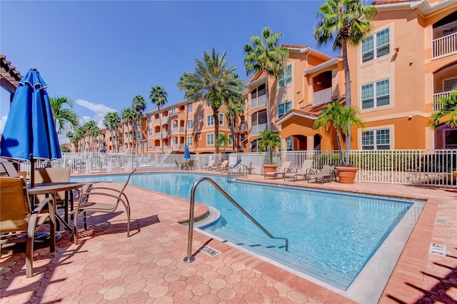 community pool with a patio area and fence