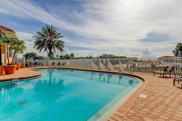 community pool with a patio area and fence