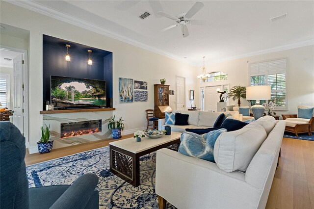 living area with a high end fireplace, visible vents, wood finished floors, and ornamental molding