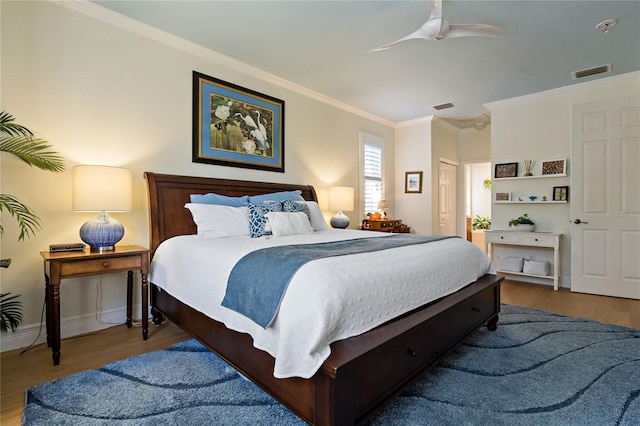 bedroom featuring visible vents, crown molding, and wood finished floors