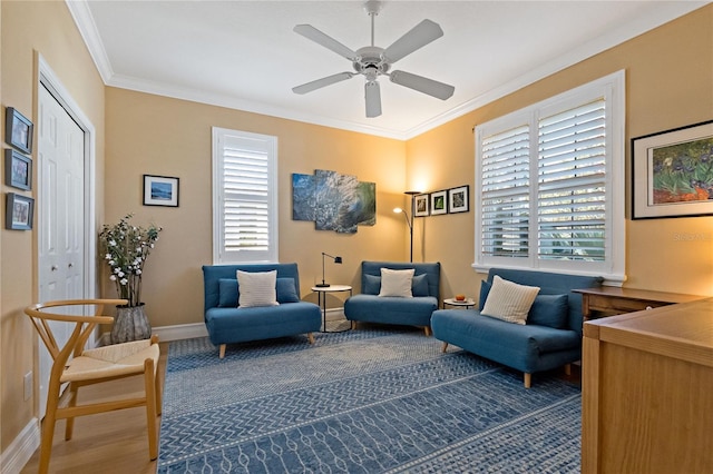 living area with ornamental molding, a wealth of natural light, baseboards, and a ceiling fan